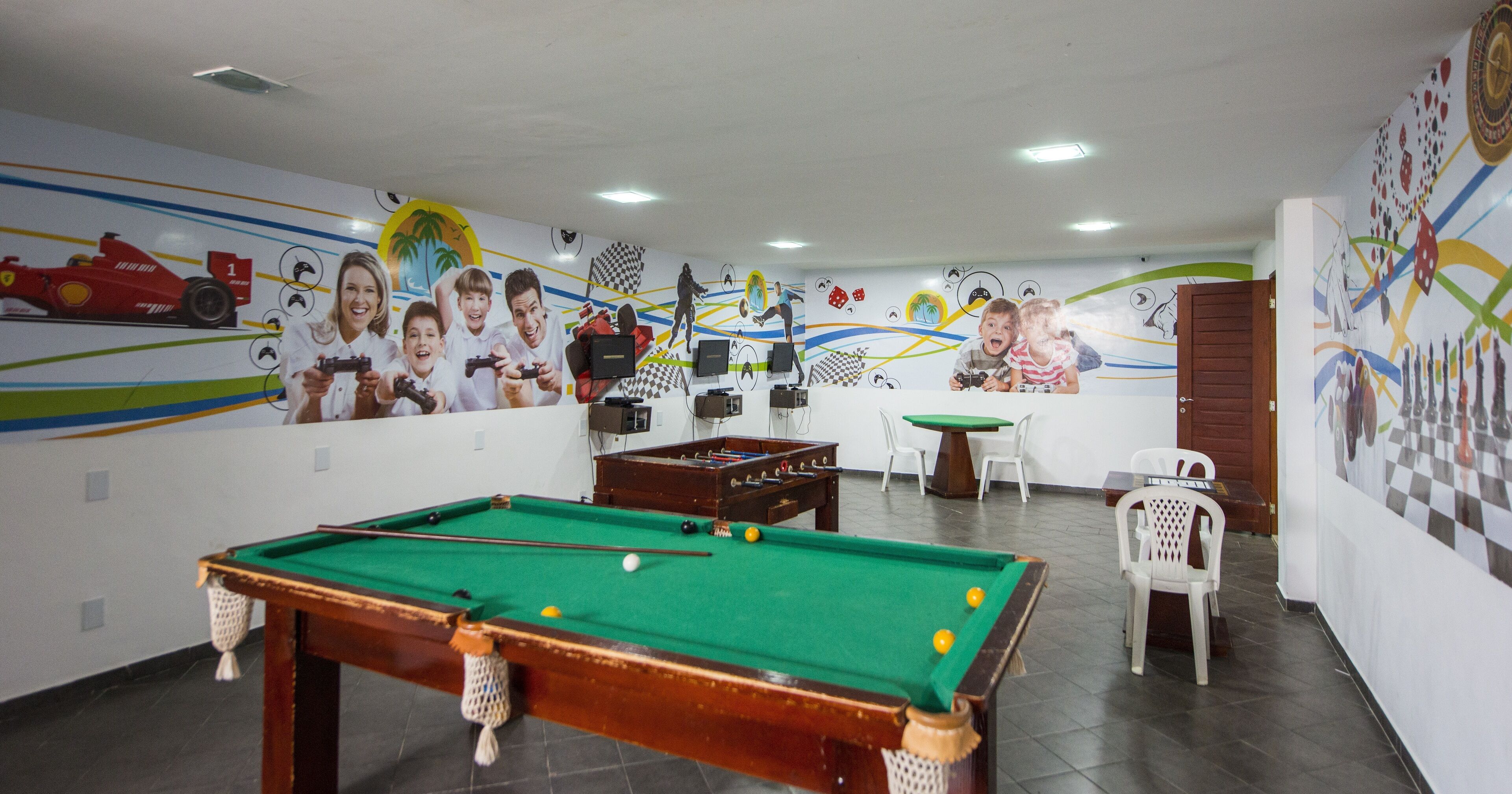 A pool table in a room with a mural of racing cars and a pool table.