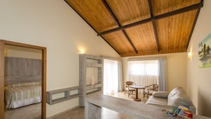 Una habitación con techo de madera, sofá, mesa de comedor y cama.