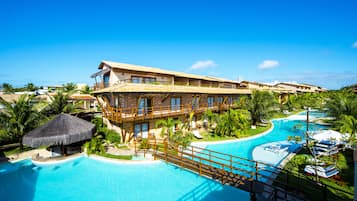 Relax by the resort's large pool surrounded by lush greenery and palm trees, with scenic views from the multi-story building's balconies.