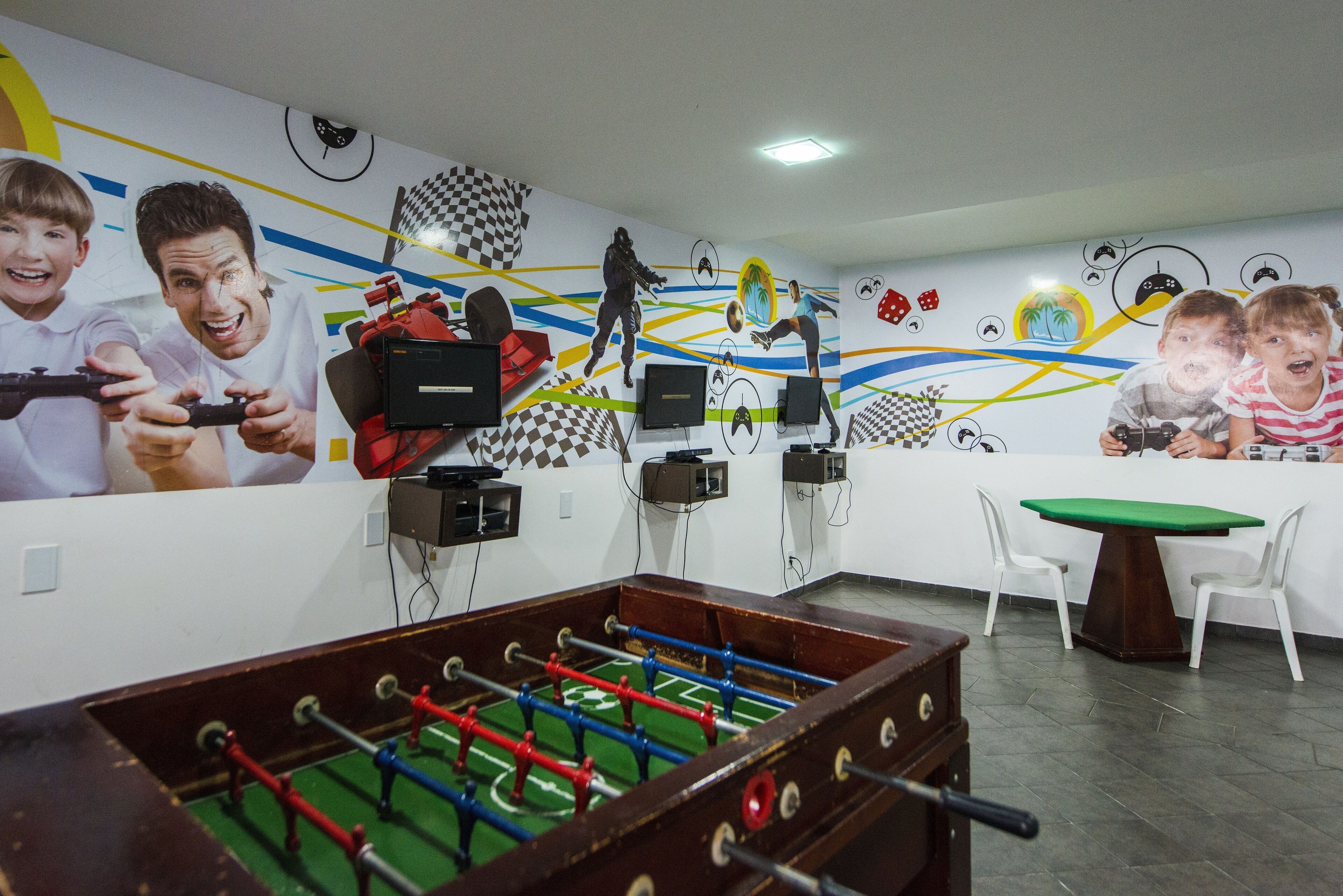 Une pièce équipée d’un baby-foot, d’une télévision et d’un mur décoré de fresques sur le thème des jeux vidéo et du sport.