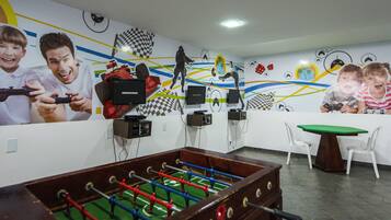 Une pièce équipée d’un baby-foot, d’une télévision et d’un mur décoré de fresques sur le thème des jeux vidéo et du sport.