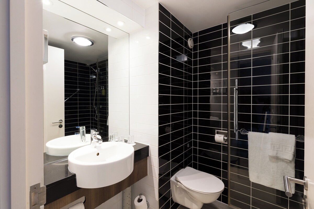 A modern bathroom with two sinks, a toilet, and a glass-enclosed shower.