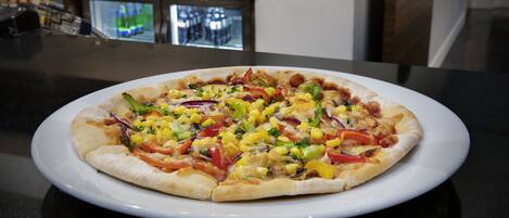 Una pizza sobre un plato blanco sobre una encimera negra.