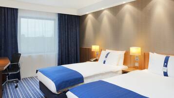 A hotel room with two beds, a desk, and a chair.