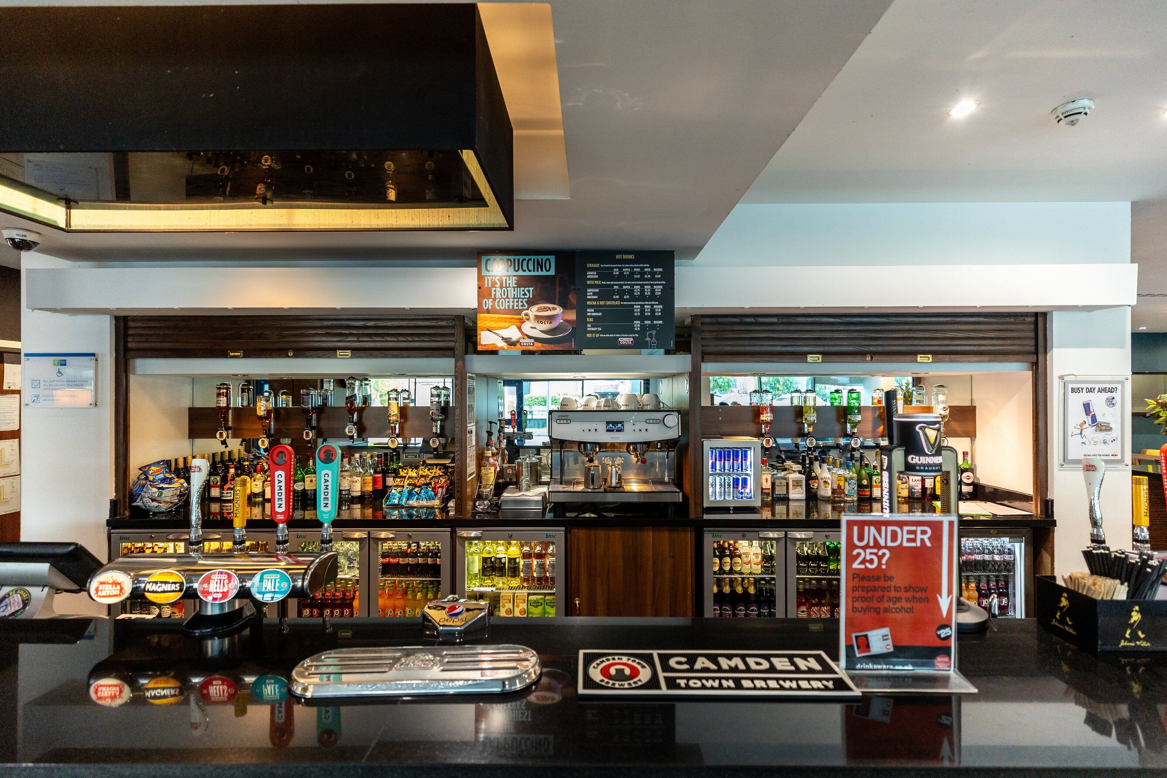 Een bar met verschillende tappunten, flessenrekken en een bord dat een leeftijdsrestrictie aangeeft.