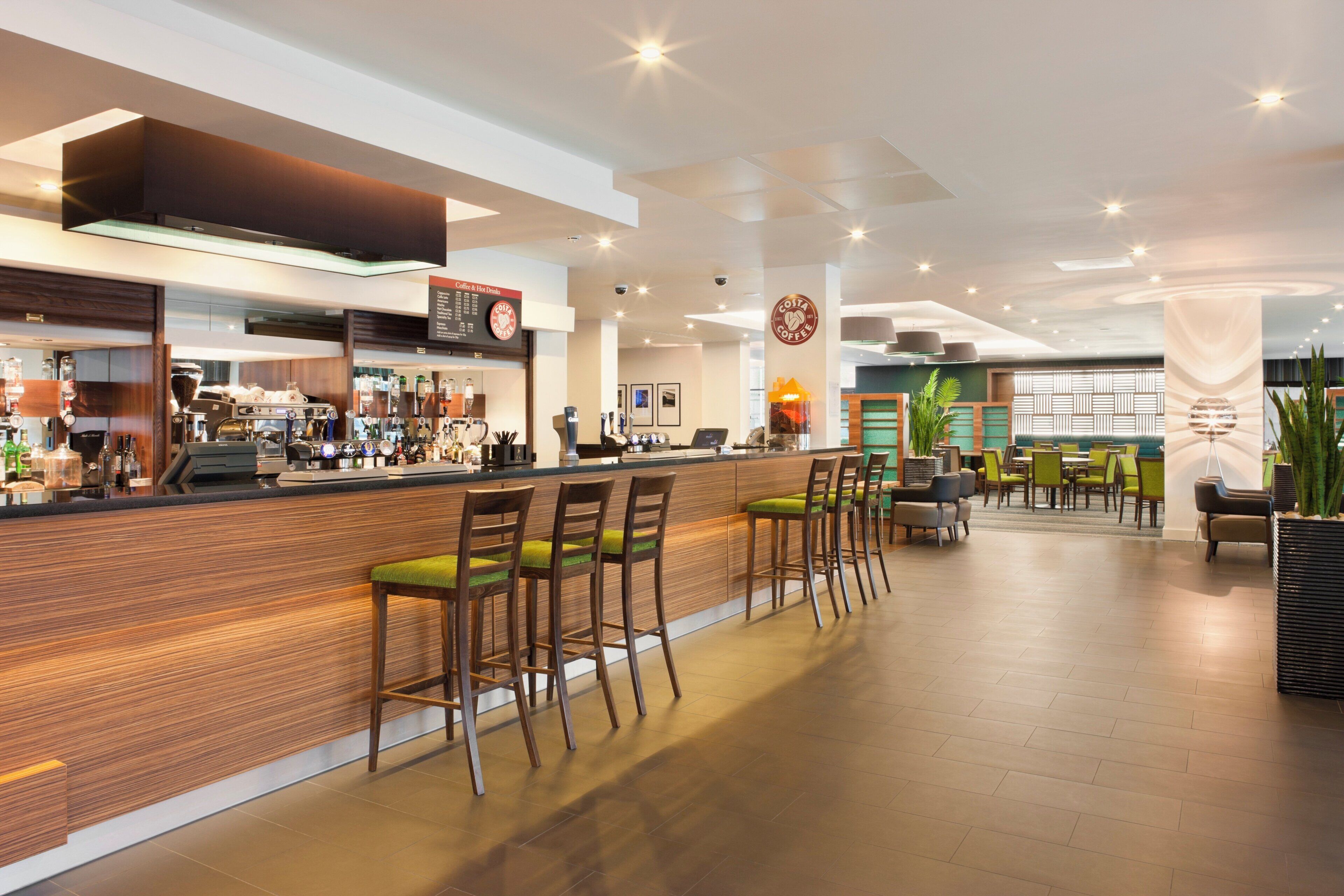 A modern bar area with wooden bar stools and a coffee machine.