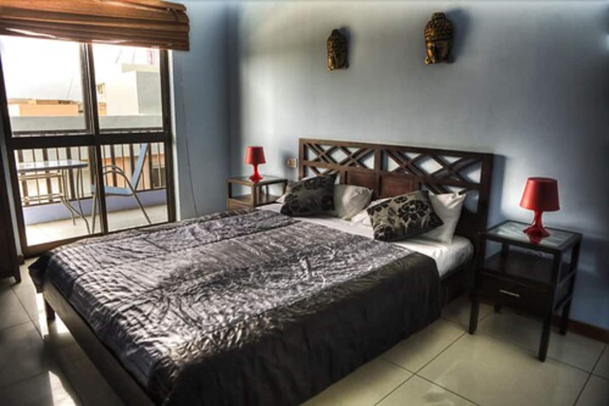 A bedroom with a bed, two nightstands, a window with a view, and decorative wall art.