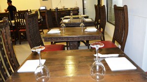 Un restaurant amb taules i cadires de fusta, cadascuna amb un got de vi i una tovallola.