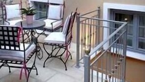 A patio with a table and chairs, a potted plant, and a stone wall. - Arxontiko Pepos (Nafpaktos)