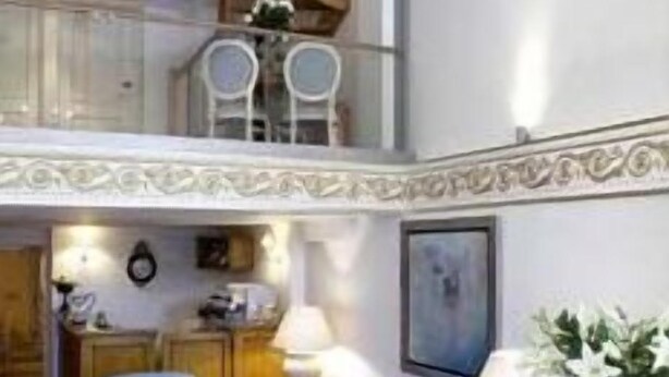 A spacious living area with a high ceiling, a chandelier, a dining table, and a blue sofa. - Arxontiko Pepos (Nafpaktos)