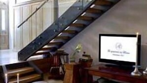 A modern living room with a staircase, a television, and a seating area. - Arxontiko Pepos (Nafpaktos)