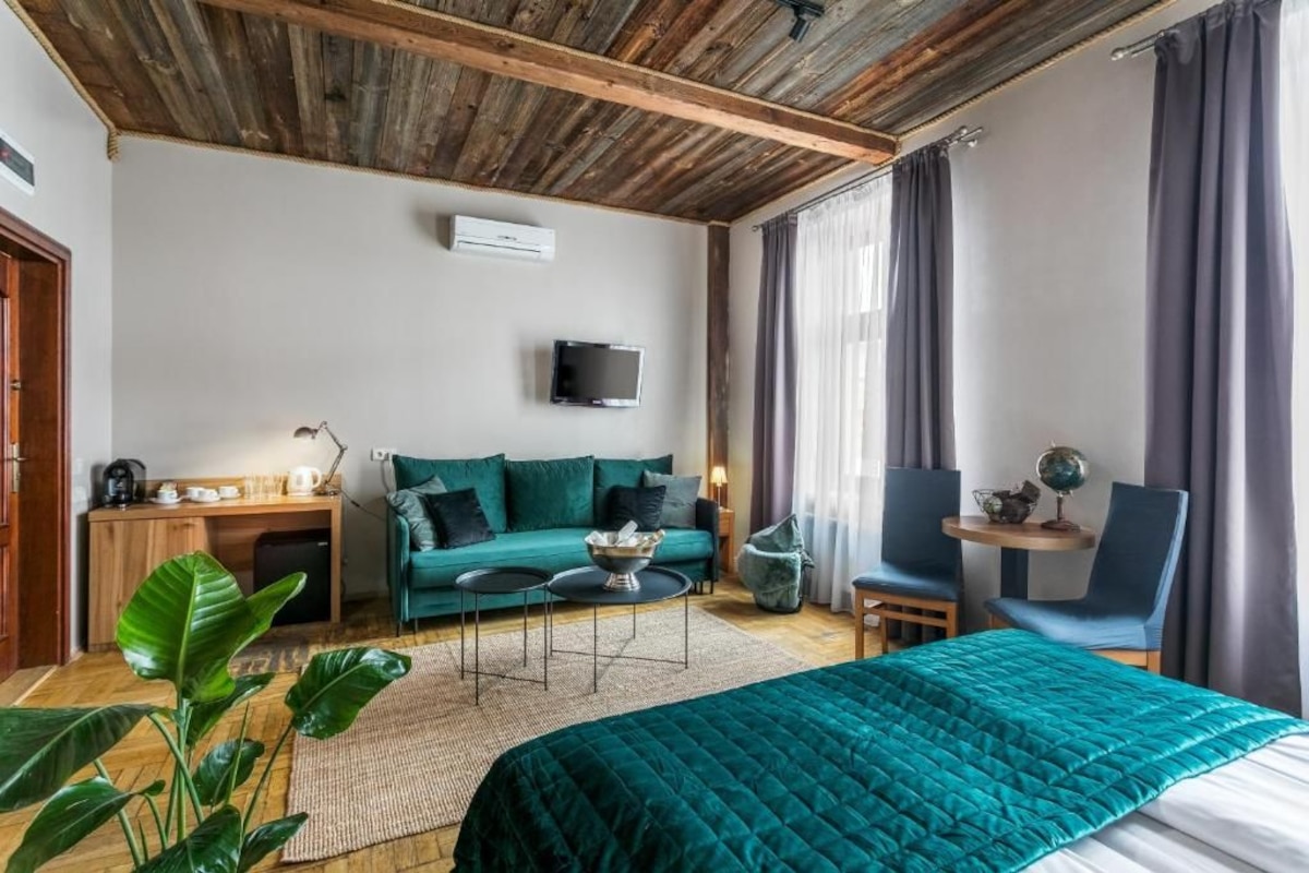 A cozy room with a bed, a sofa, a small table, and a TV.