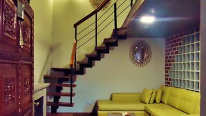 Una sala de estar con una escalera de madera, un sofá verde y una mesa de centro.