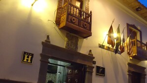 Un edificio con un balcón, una puerta y un letrero con la letra 'H'.