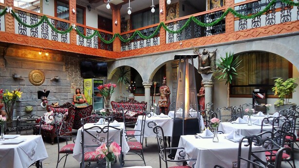 Un restaurante con terraza, barandillas ornamentadas y una chimenea decorativa.