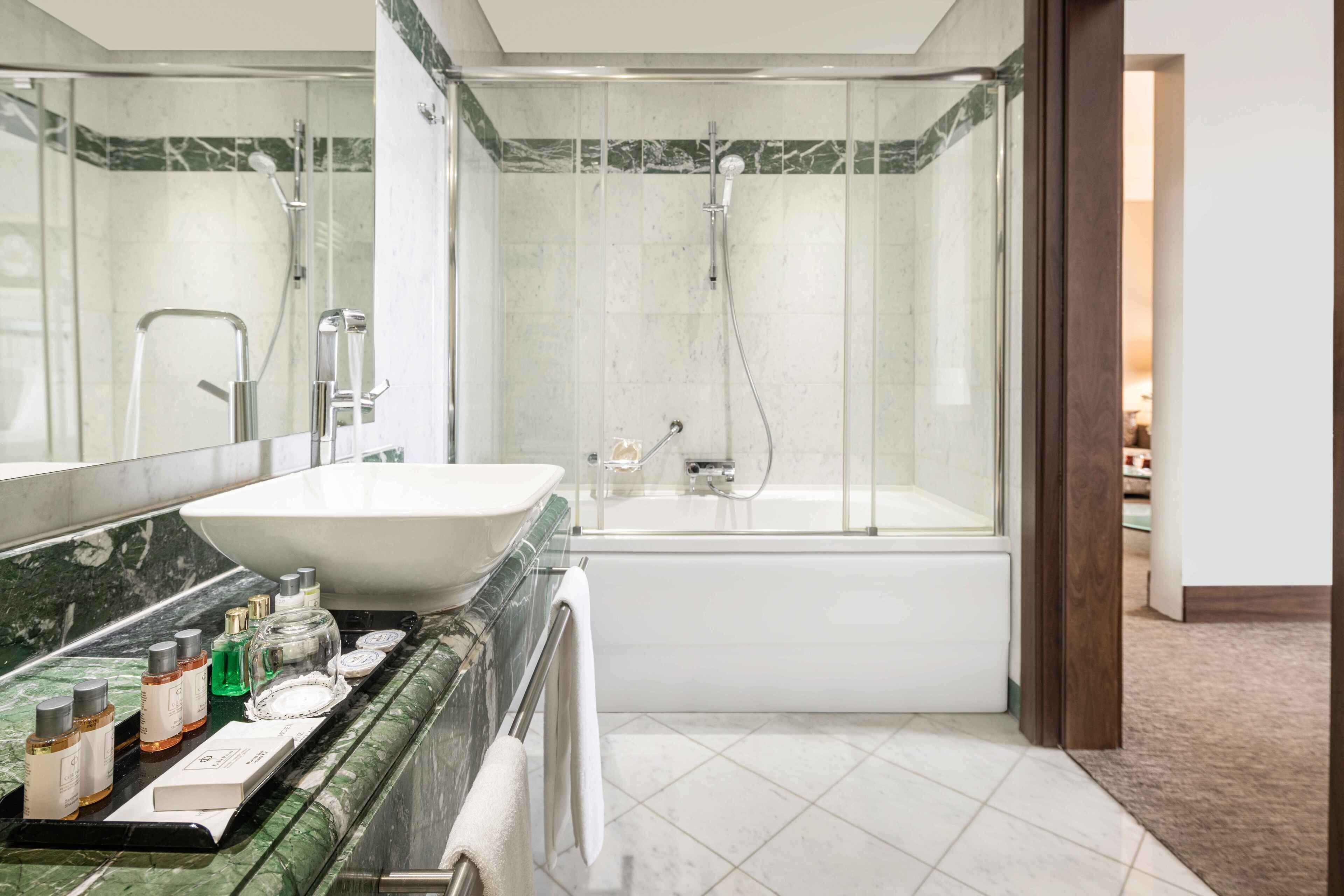 Un baño moderno con un lavamanos grande, espejo y cabina de ducha con mampara de vidrio.