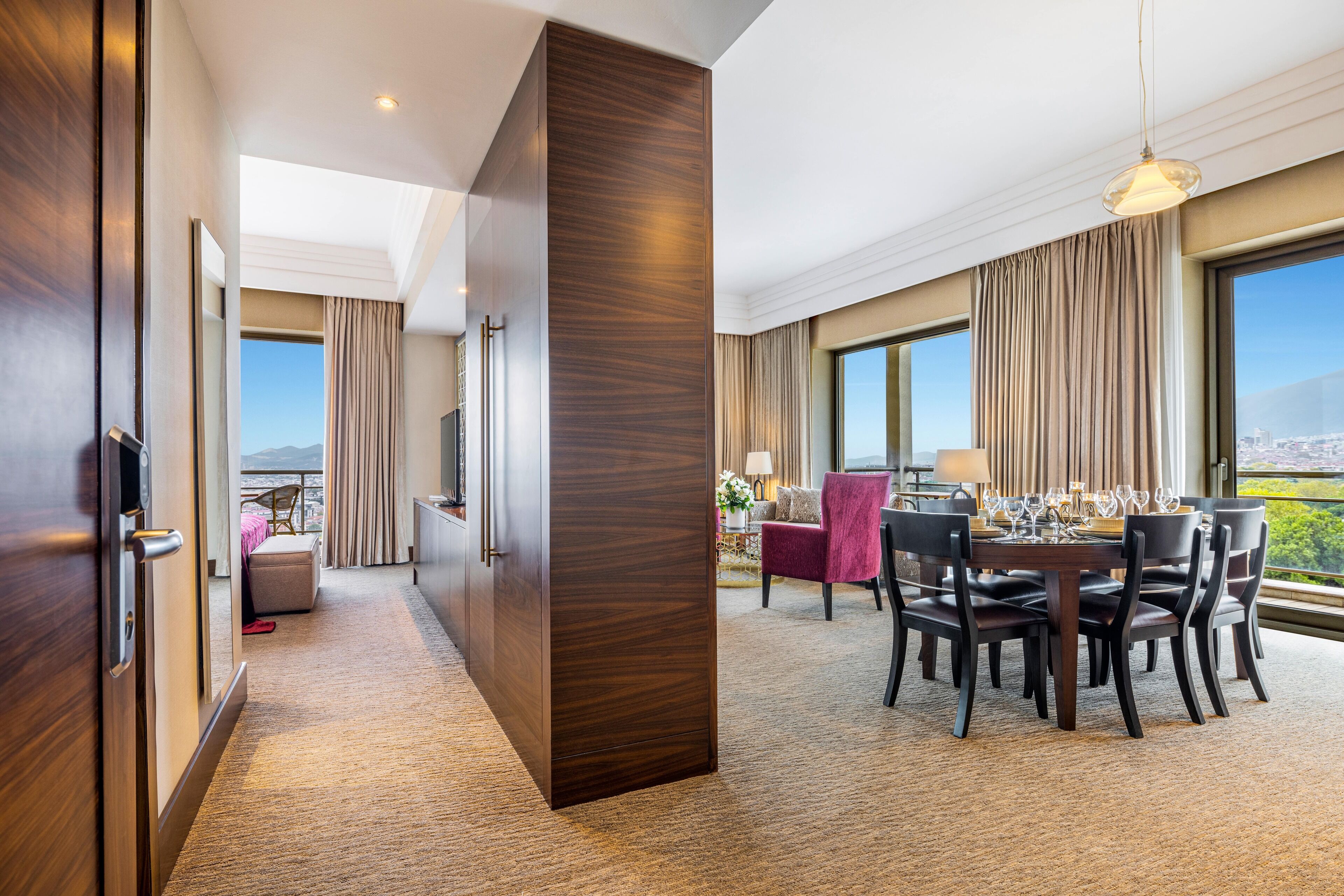 Une chambre d’hôtel avec un coin repas, de grandes fenêtres et une vue sur la ville.