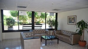 A spacious lobby with a sofa, a coffee table, and potted plants. - Agrino Hotel Apartments (Ayia Napa)