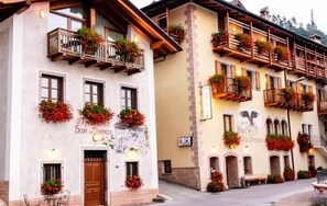 Hotel con balcones decorados con flores y un letrero que dice 'Hotel San Lorenzo', con un estilo arquitectónico tradicional.