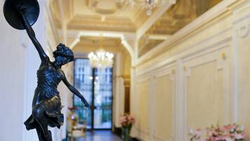 Un amplio pasillo con una estatua, candelabros y arreglos florales.