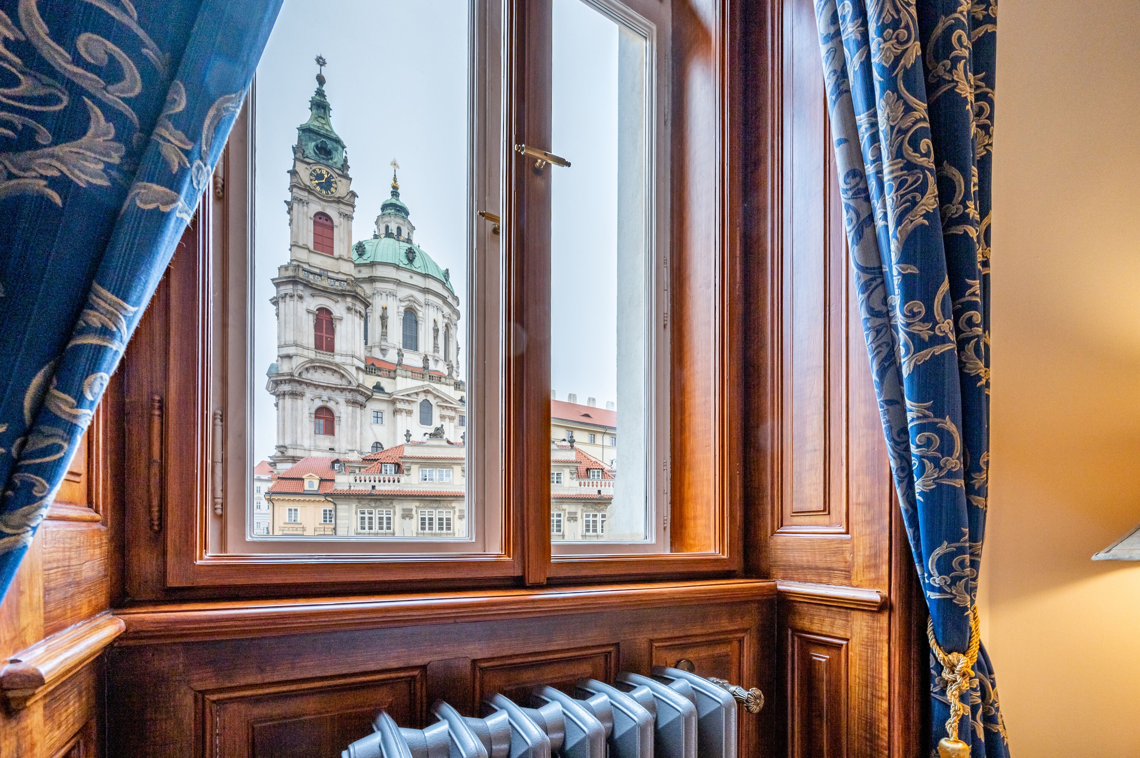 A window with a view of a historic building with a clock tower and domes.