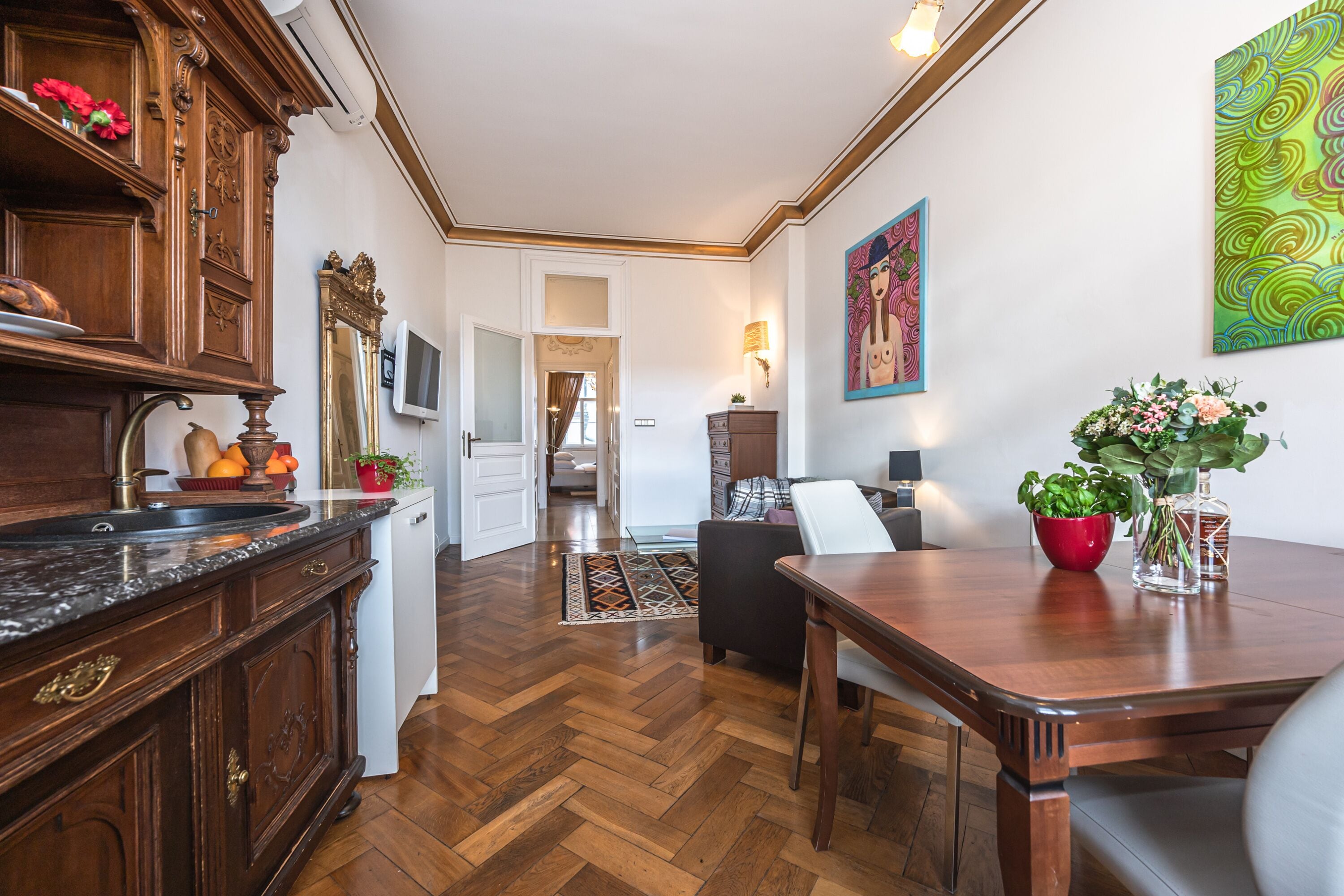 Een ruime keuken met houten kastjes en een marmeren aanrechtblad, dat uitkomt op een eetgedeelte met een houten tafel en stoelen.