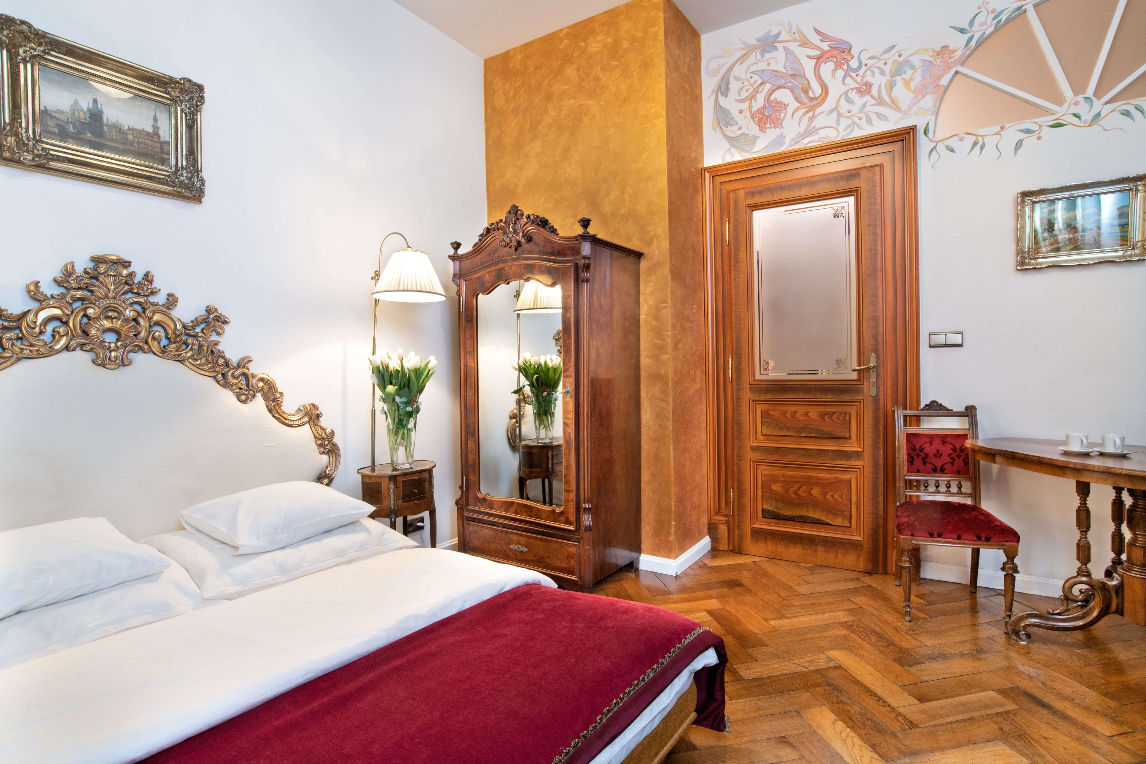 Quarto com uma cama grande, penteadeira de madeira, espelho, cadeira e escrivaninha.