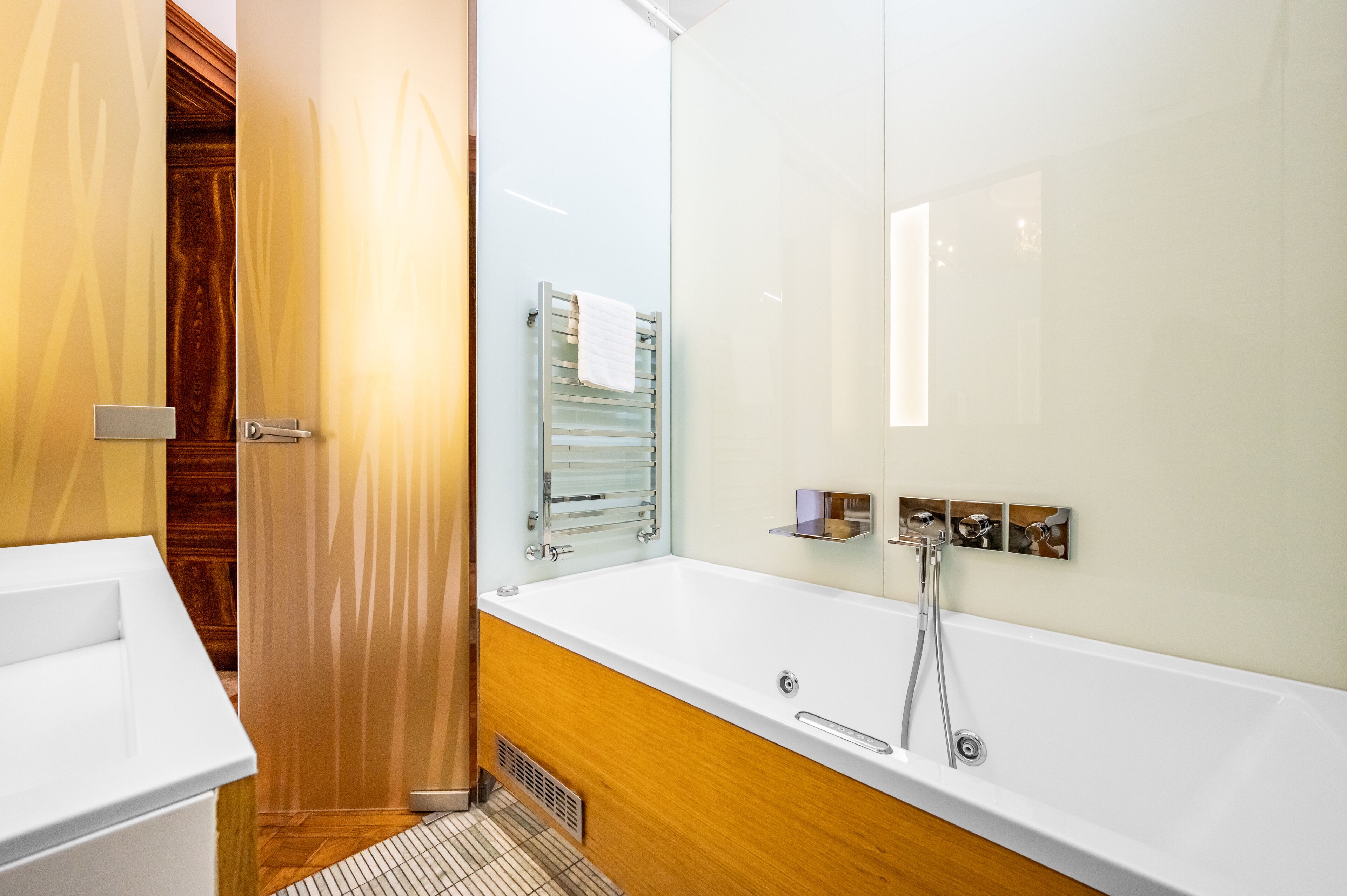 Un baño moderno con tocador de madera, una bañera blanca y cabina de ducha con paredes de vidrio.