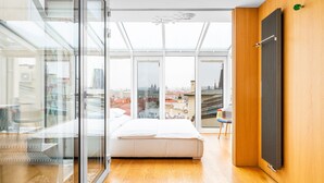 Un dormitorio moderno con una cama grande, un muro de cristal y vistas a la ciudad.