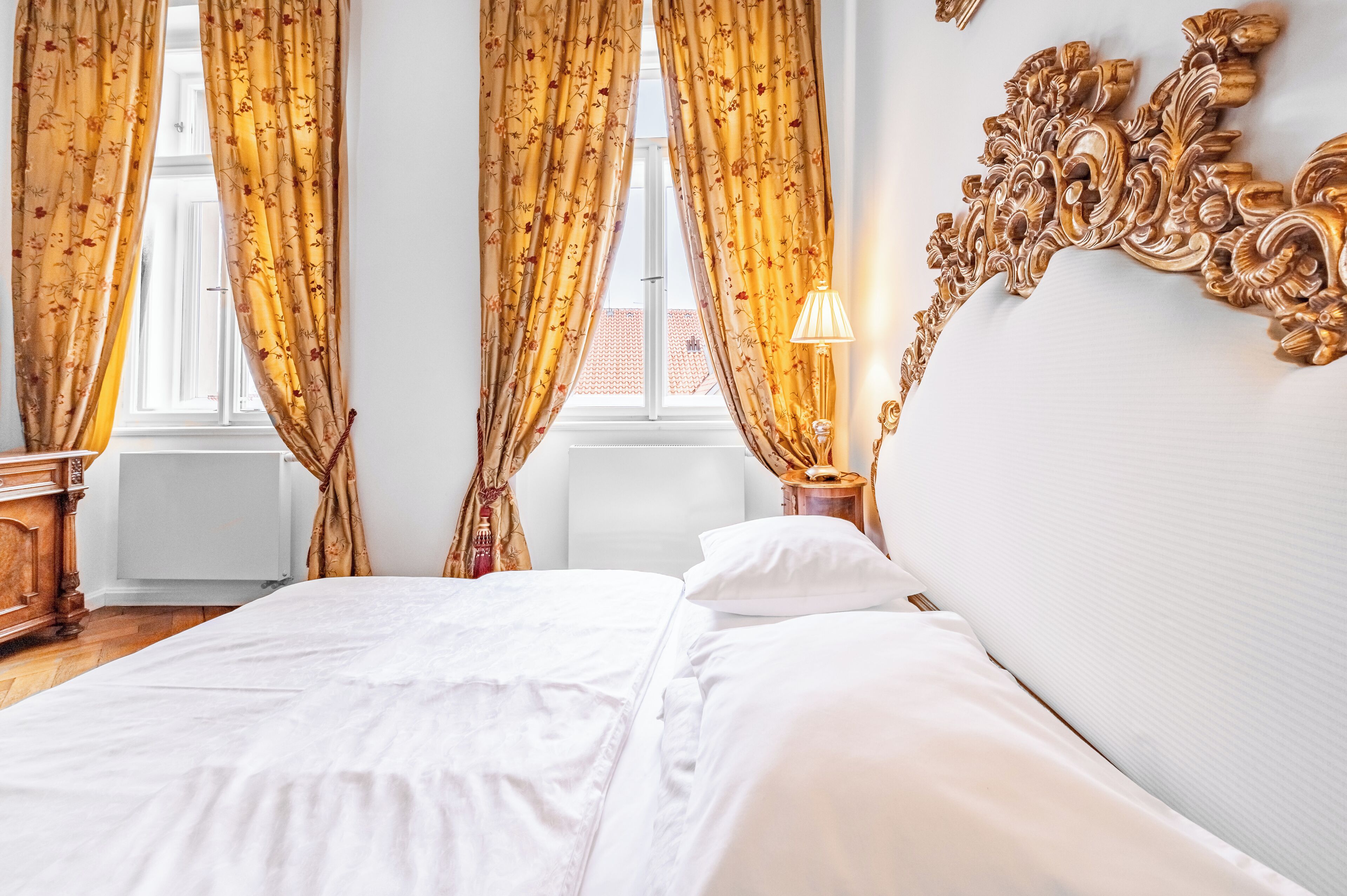 Ein Hotelzimmer mit Bett, Vorhängen, einer Lampe und einem dekorativen Wandbild.