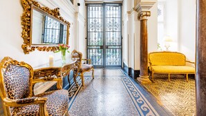 Un amplio pasillo con muebles ornamentados, un espejo grande y un suelo con diseño.