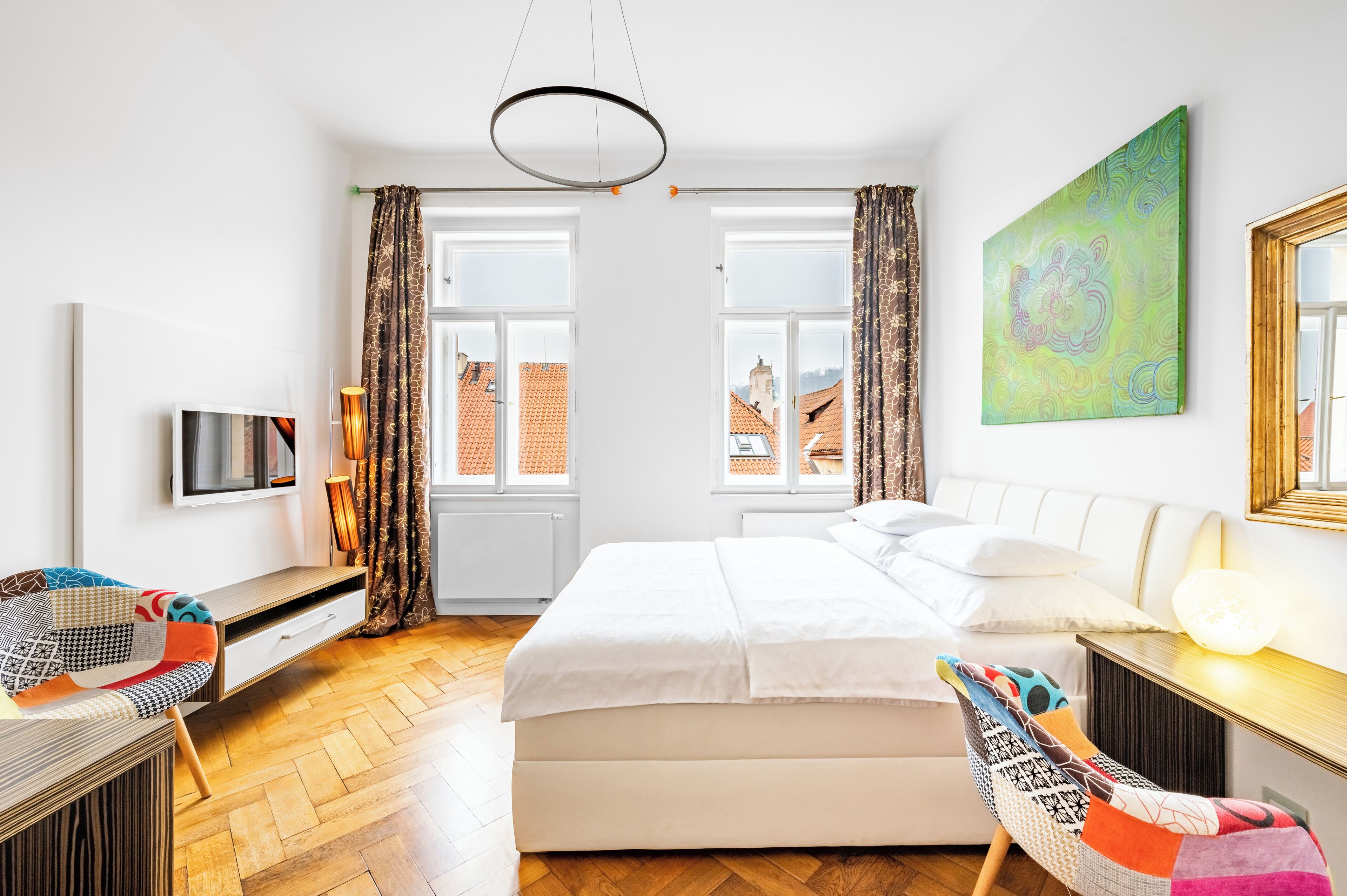 A modern bedroom with a large bed, a desk, a chair, and a television.