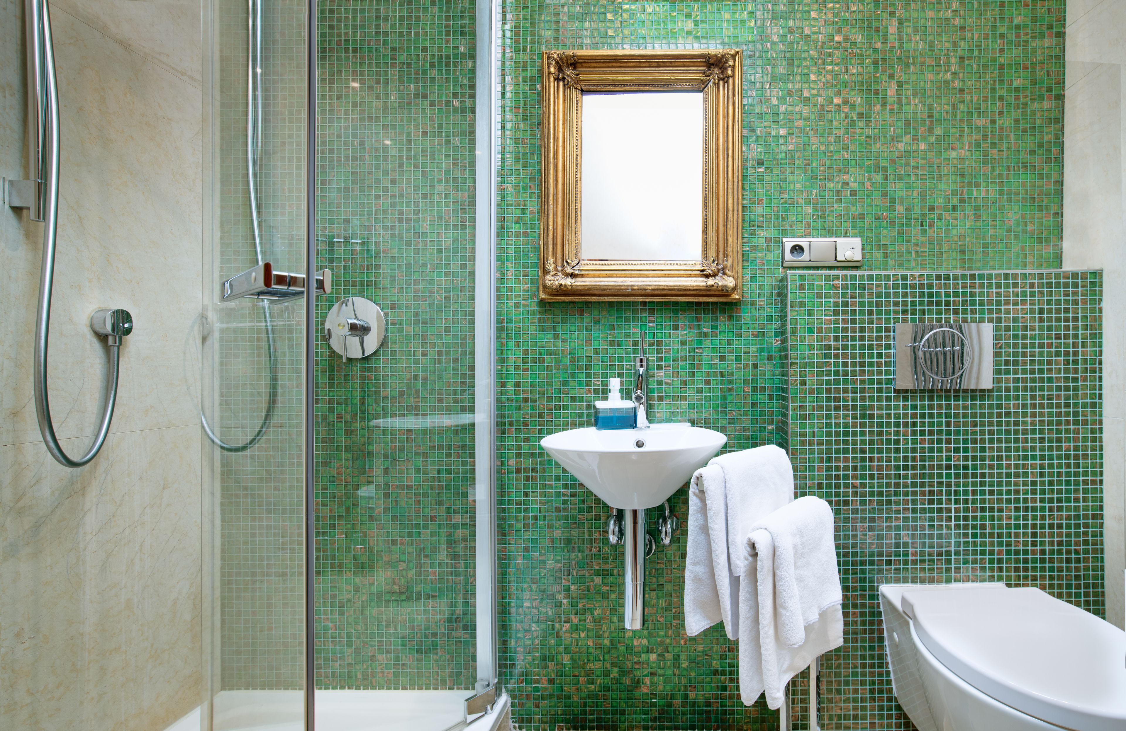 A bathroom with a glass shower enclosure, a sink with a mirror, and a toilet.