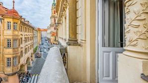 Una calle estrecha con edificios históricos, una imponente torre del reloj y cielo despejado.