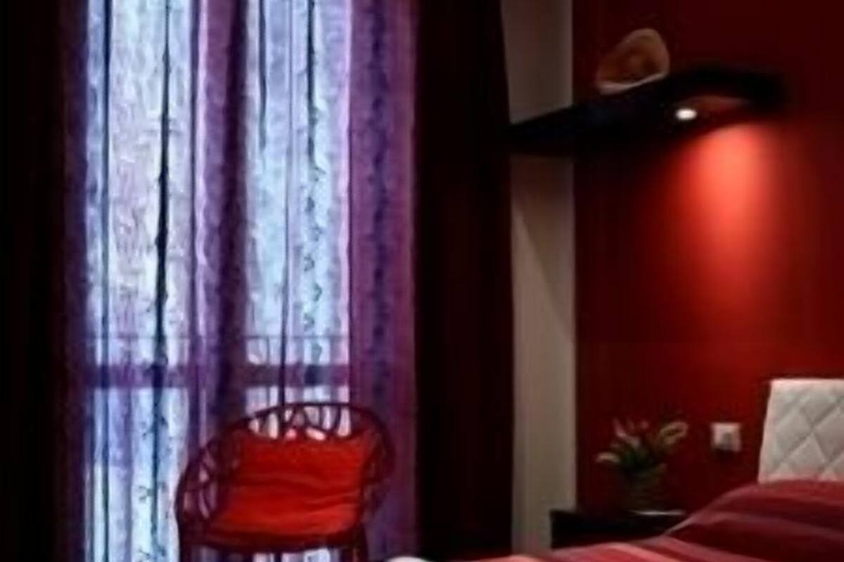 Una habitación de hotel con una cama, una silla y una mesita de noche.