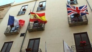 Un edificio con múltiples balcones, cada uno decorado con banderas de diferentes países.