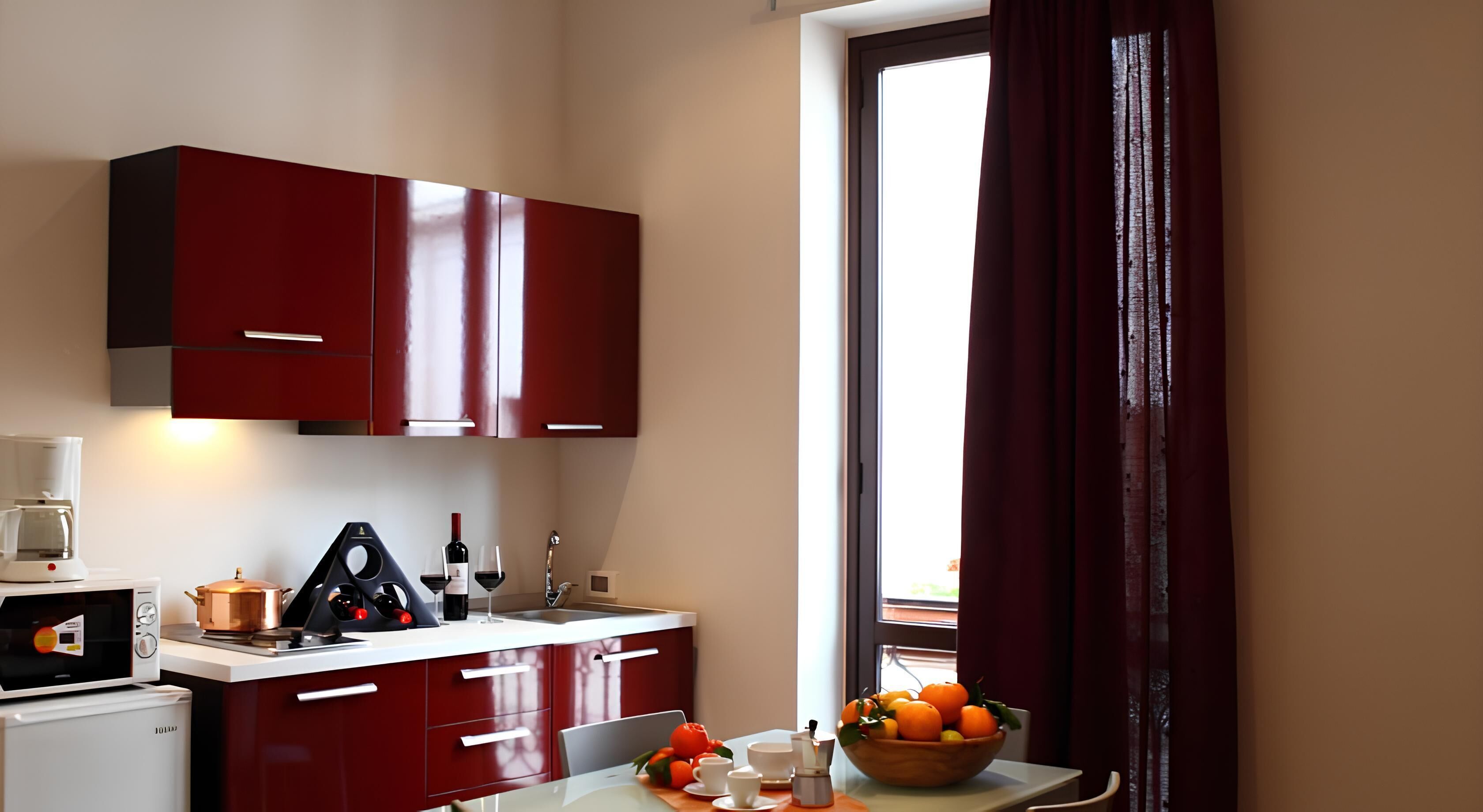 Une cuisine de taille réduite avec des placards rouges, une machine à café, un four à micro-ondes et un évier.