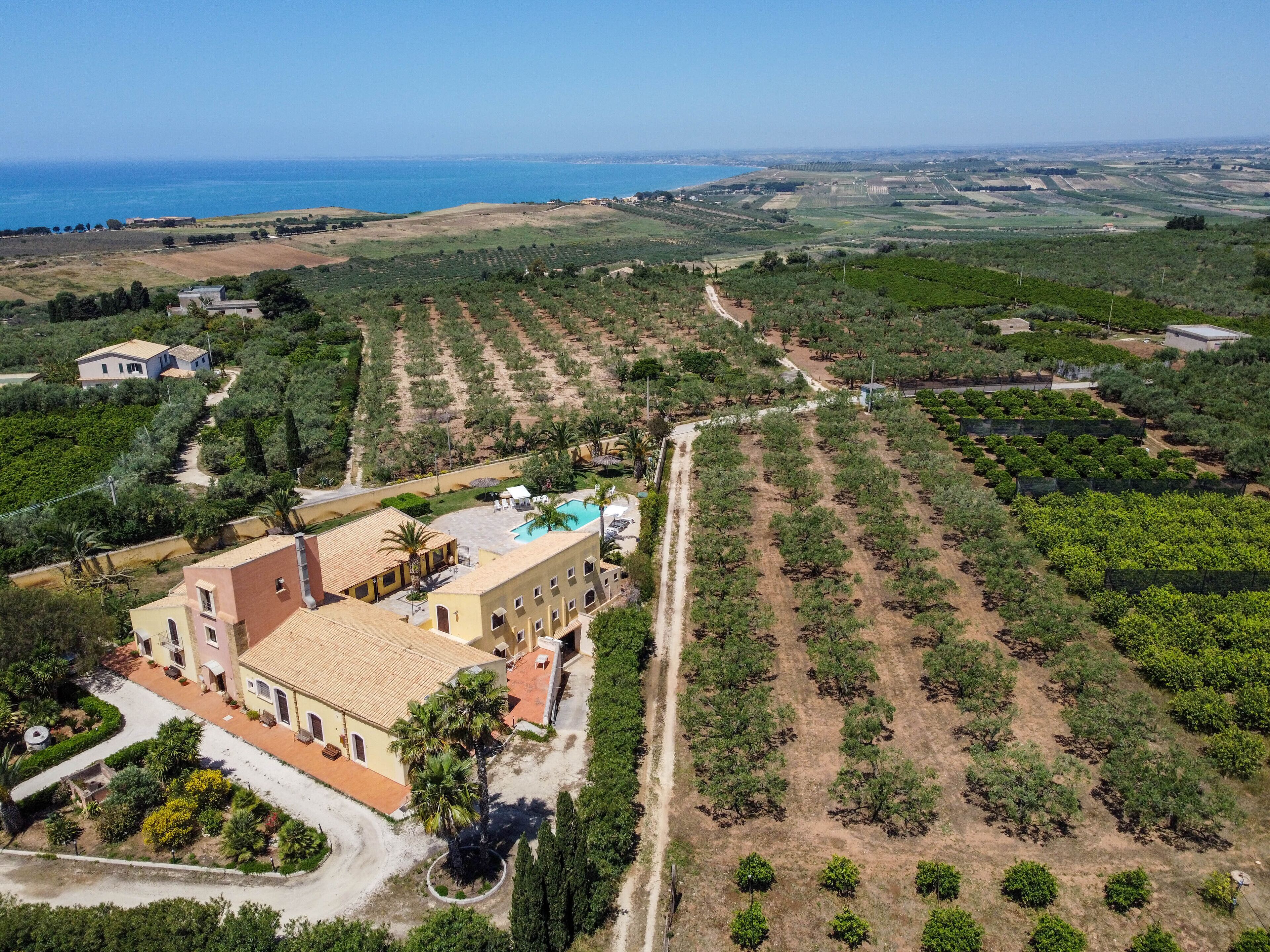 An aerial view of a property with a large building, a swimming pool, and terraced fields.