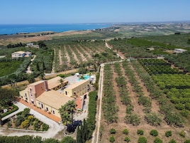 An aerial view of a property with a large building, a swimming pool, and terraced fields.