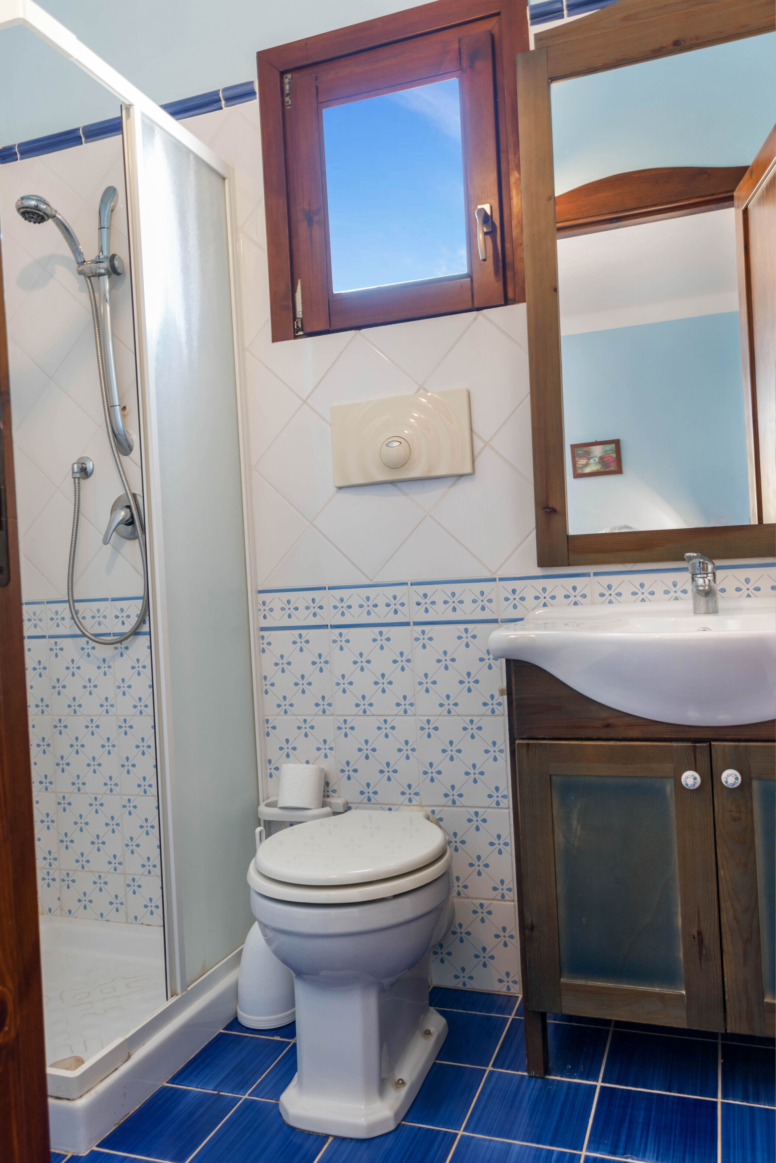 Un bagno con doccia, toilette, lavandino e specchio sopra il lavandino.