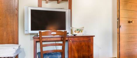 A bedroom with a wooden desk, a chair, a bed, and a wardrobe.