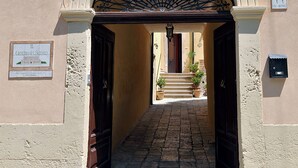 Entrada empaveda en piedra a un edificio con una reja de hierro forjado y un cartel con el número de la dirección.