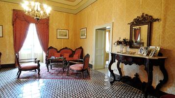 Una habitación con baldosas de diseño, un candelabro, un espejo y una mesa con cuadros enmarcados.