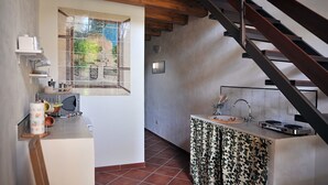 Una cocina con ventana, un lavamanos y una escalera.