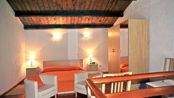 Ein Schlafzimmer mit Holzboden, einem Bett mit orangefarbener Bettwäsche, zwei Nachttischen mit Lampen und einem Holzstuhl.