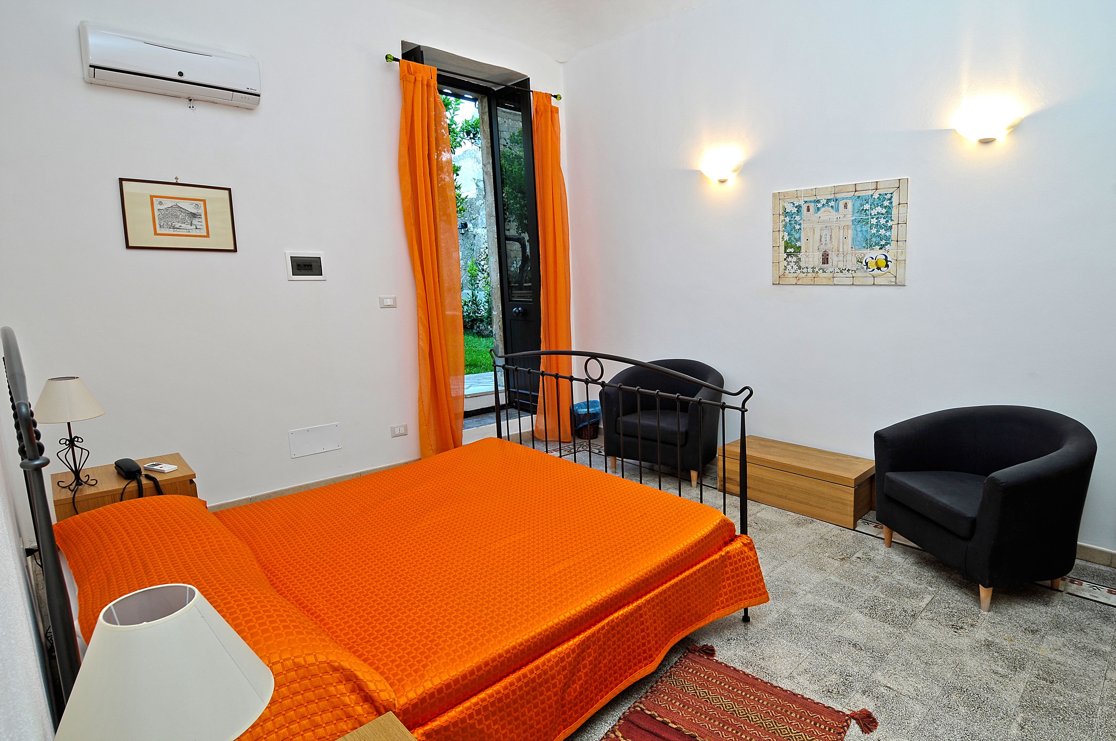Un dormitorio con una cama, una silla, un escritorio y una ventana con cortinas.