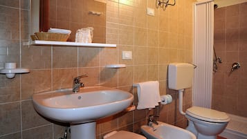 A bathroom with a sink, toilet, bidet, and shower.