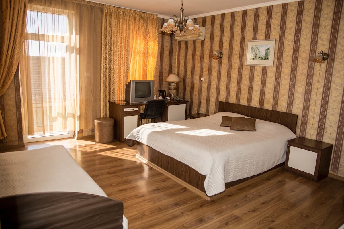 Une chambre d’hôtel avec un grand lit, un bureau avec un ordinateur, une chaise et une petite table.