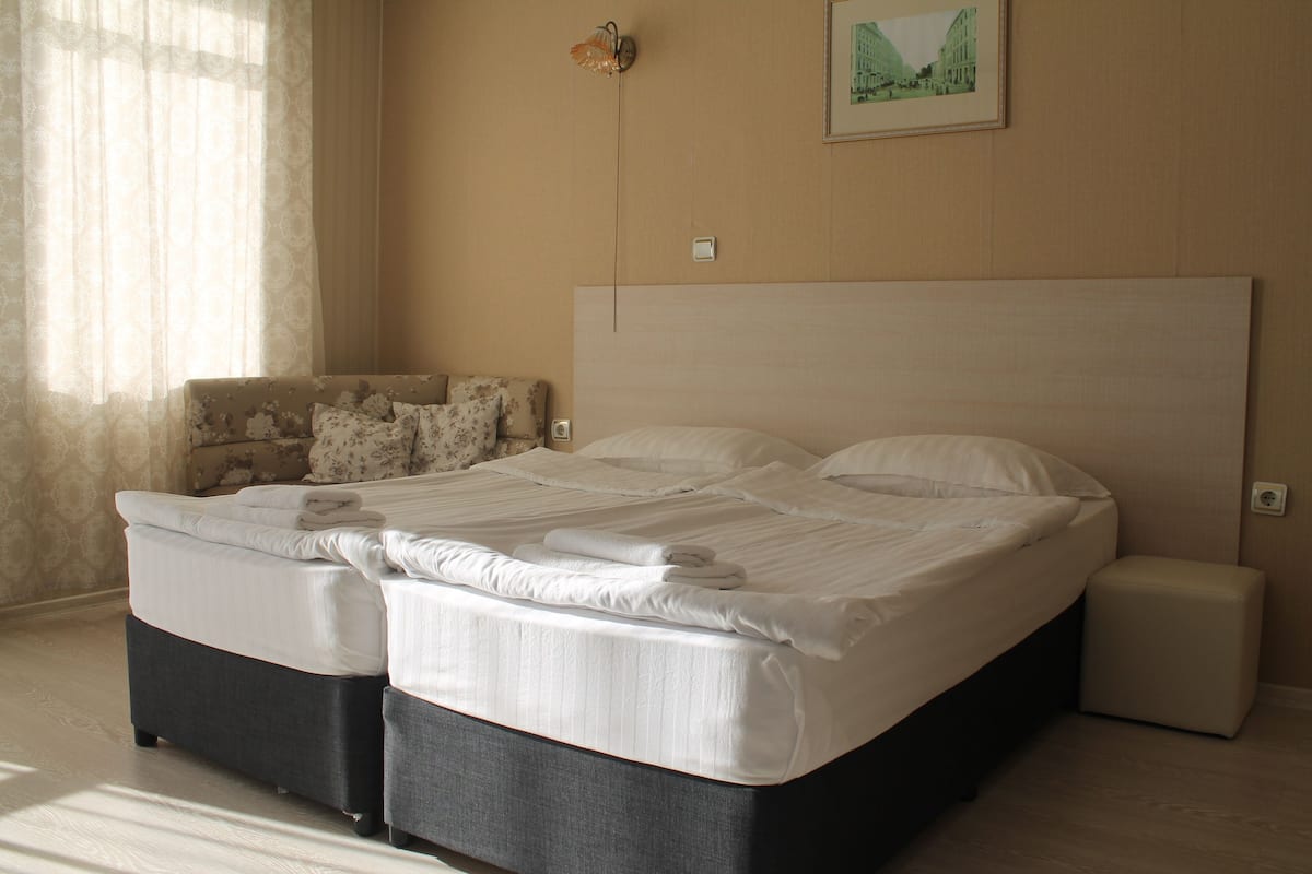 Un lit double avec une tête de lit, une table de chevet et une chaise avec des coussins.