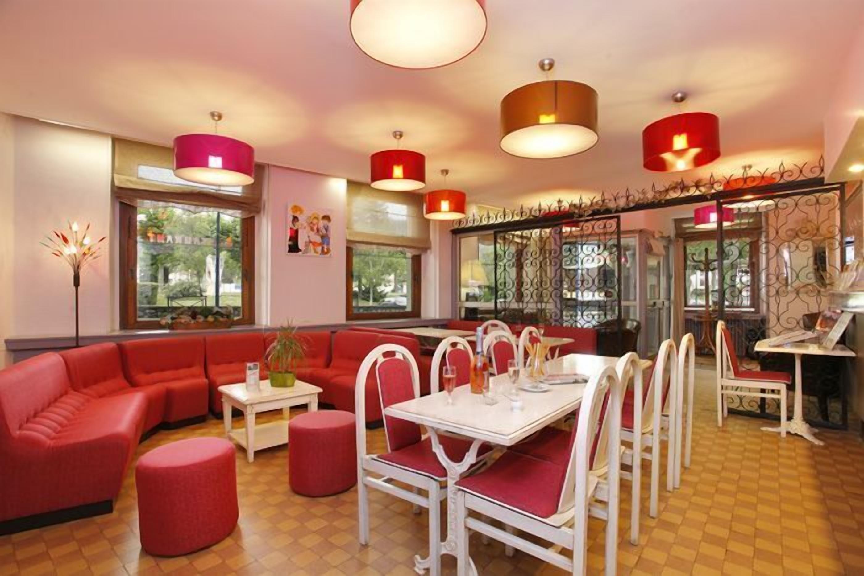 A dining area with red sofas, white chairs, and a central table.